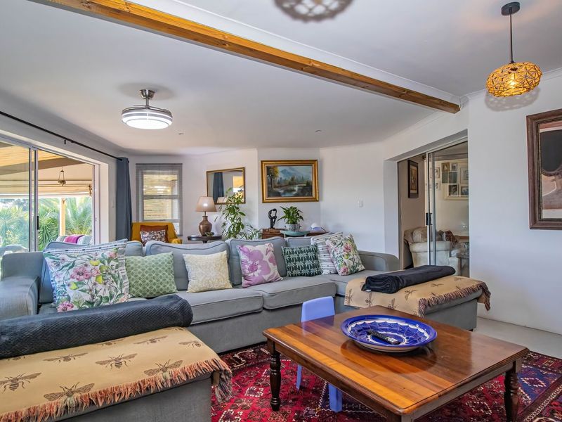 A comfortable living room featuring an exposed timber ceiling beam, recessed lighting, and large sliding glass doors that provide access to the outdoor patio area.