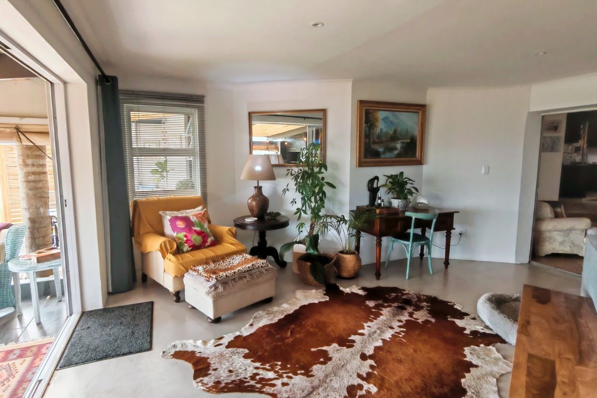 A bright living room featuring polished concrete floors, recessed lighting, and large sliding glass doors providing seamless access to the outdoor patio area.