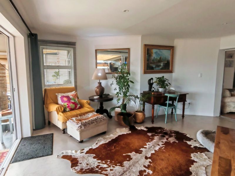 A bright living room featuring polished concrete floors, recessed lighting, and large sliding glass doors providing seamless access to the outdoor patio area.