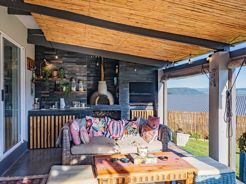 Covered patio featuring a built-in pizza oven, braai, stone-clad feature wall, and sliding door access, offering an ideal space for outdoor entertaining.