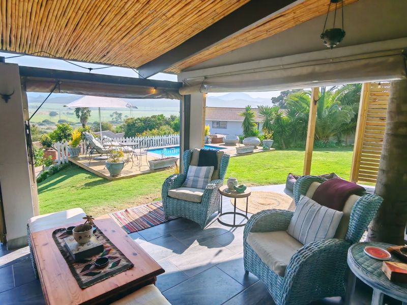 Covered outdoor patio featuring a bamboo ceiling, tiled flooring, and open views overlooking the garden and swimming pool area.