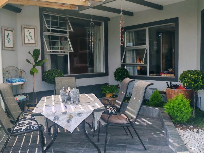A covered outdoor patio area featuring tiled flooring and a timber pergola, providing a pleasant space for outdoor dining and relaxation.