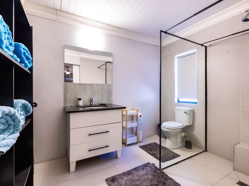 Modern bathroom featuring a vanity with stone countertop, walk-in shower with black-framed glass screen, and tiled flooring.