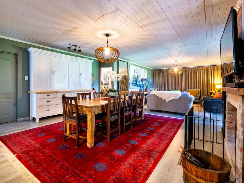 Spacious open-plan living and dining area featuring a brick fireplace, built-in cabinetry, and a distinctive tongue and groove ceiling.