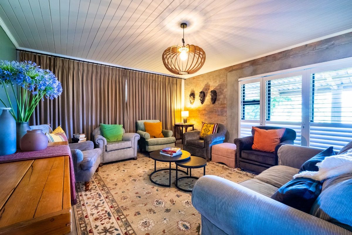 A cozy living room featuring an exposed brick feature wall, timber panelled ceiling, and shutter blinds, creating a warm and inviting atmosphere.