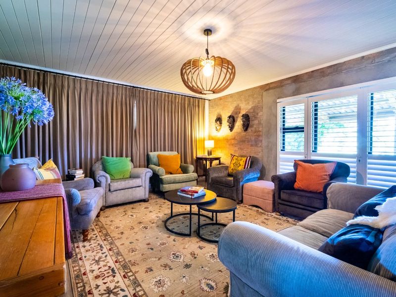 A cozy living room featuring an exposed brick feature wall, timber panelled ceiling, and shutter blinds, creating a warm and inviting atmosphere.