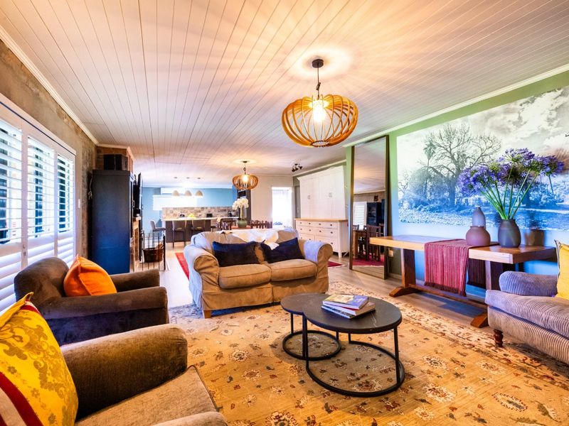 Spacious open-plan living area featuring a timber-look panelled ceiling, plantation shutters, and integrated cabinetry, flowing seamlessly into the kitchen space.