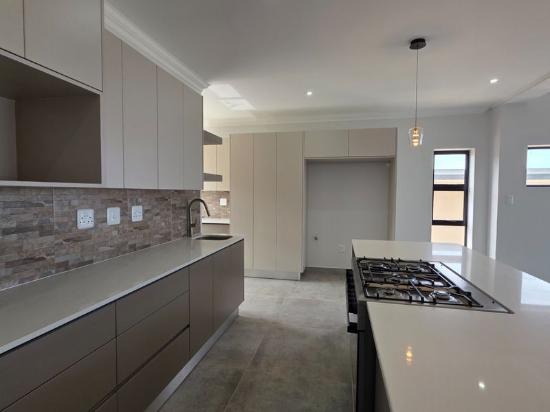 Modern kitchen featuring sleek built-in cabinetry, stone countertops, a gas hob, and a stylish tiled backsplash in a clean, contemporary space.