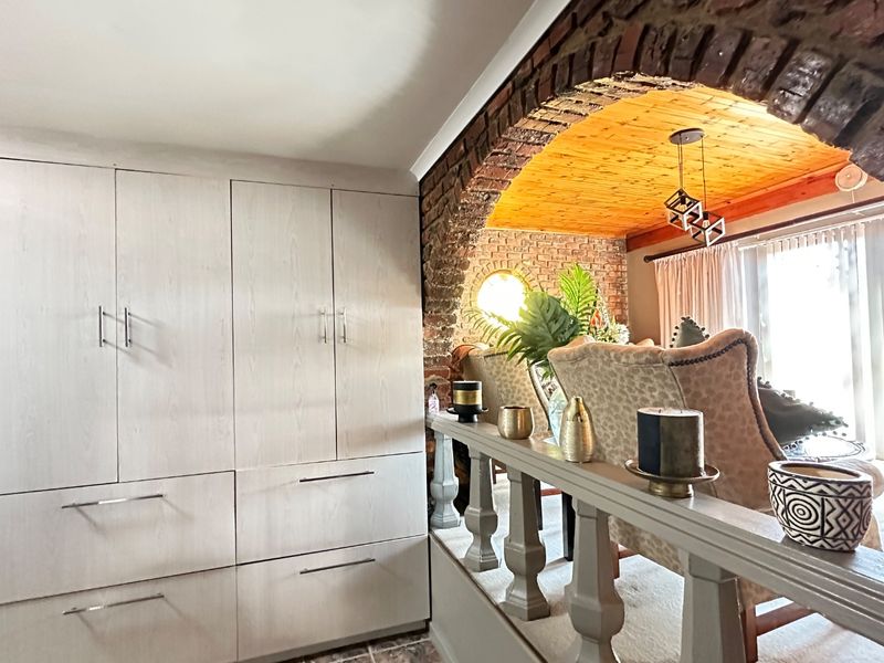 Living area featuring a distinctive exposed brick archway, timber ceiling, and integrated built-in cabinetry providing ample storage space.