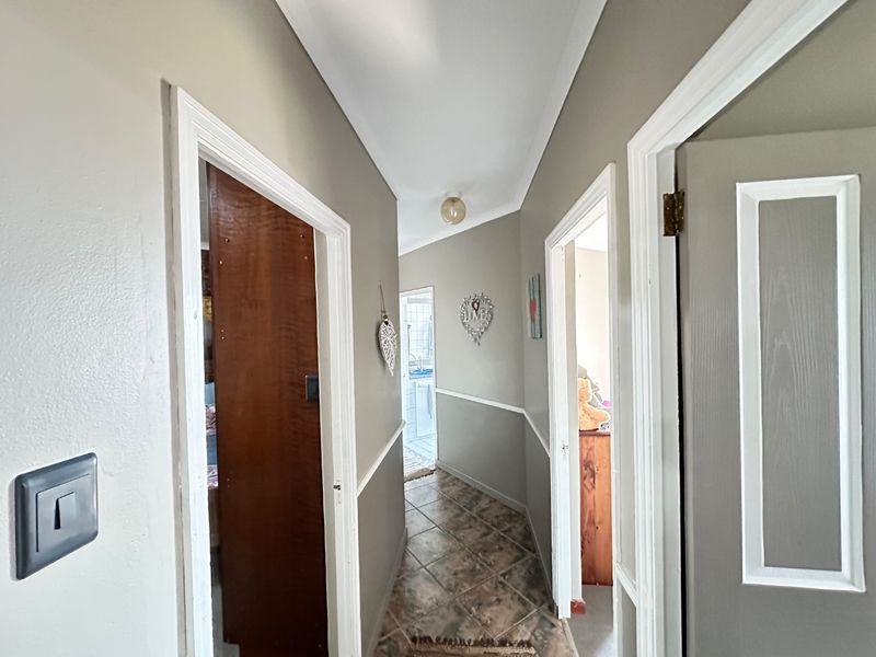 A functional hallway featuring tiled flooring, chair rail molding, and access to multiple rooms throughout the home.