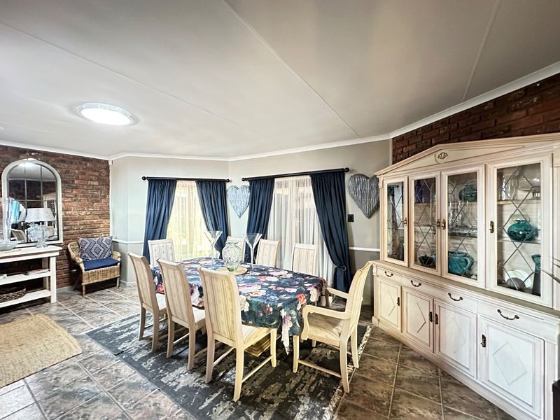 A dining room featuring exposed brick walls, tiled flooring, and sliding glass doors providing natural light.
