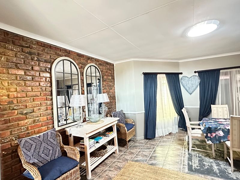 Dining area featuring an exposed brick feature wall, tiled flooring, and natural light through large windows.