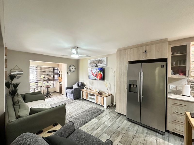 An open-plan living area featuring modern tiled flooring, built-in cabinetry, and a ceiling fan, creating a functional and cohesive space.
