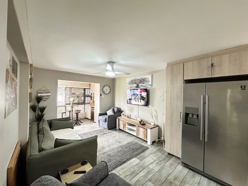 An open-plan living area featuring modern tiled flooring, a ceiling fan, and integrated cabinetry, creating a cohesive and functional space.