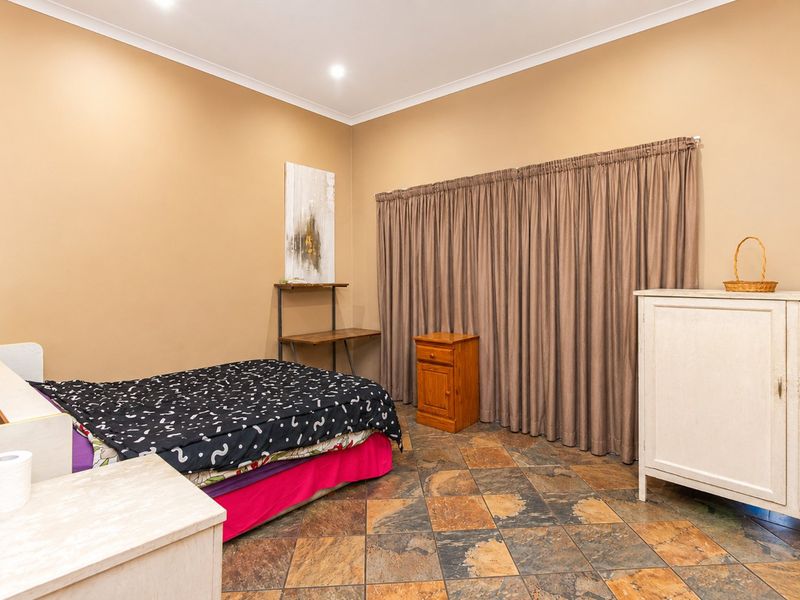 A bedroom featuring tiled flooring, neutral wall tones, and recessed downlighting, offering a functional space ready for personalization.