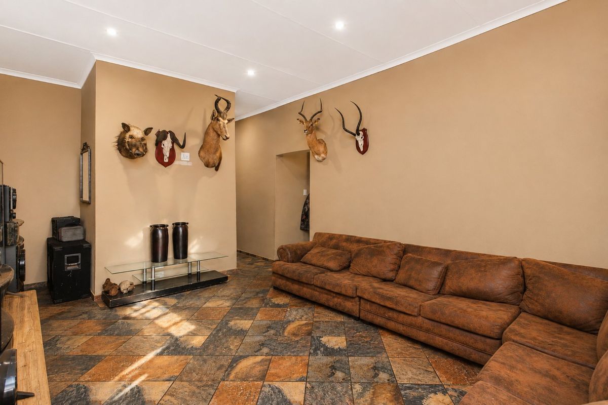 A spacious living room featuring tiled flooring, recessed downlighting, and neutral wall finishes, providing a versatile area for relaxation.