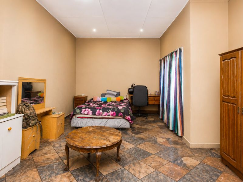 A spacious bedroom featuring tiled flooring and recessed ceiling lighting, offering a functional layout with ample space for bedroom furniture.