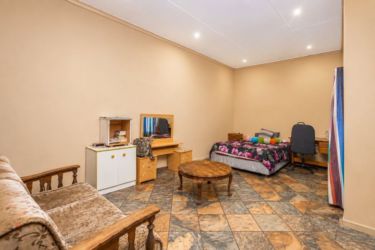 A spacious bedroom featuring tiled flooring and recessed downlighting, offering a neutral canvas for potential interior updates.