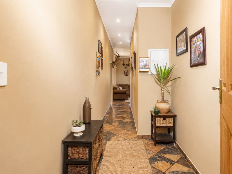 A long, well-lit hallway featuring tiled flooring and neutral wall tones, providing access to the interior living spaces of the home.