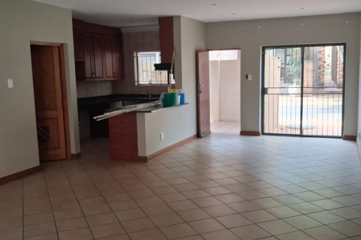 Spacious open-plan living and kitchen area featuring tiled flooring, recessed lighting, and direct access to an outdoor patio through a sliding glass door.