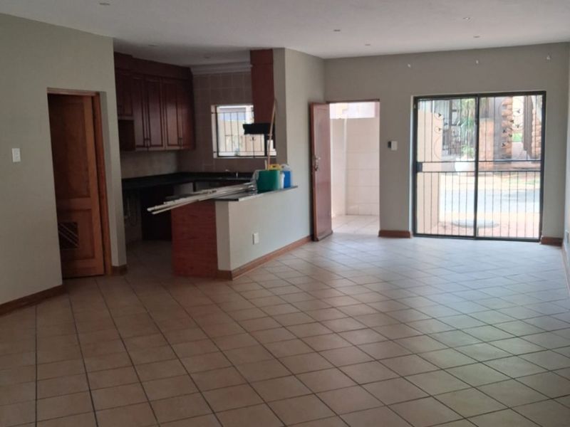 Spacious open-plan living and kitchen area featuring tiled flooring, recessed lighting, and direct access to an outdoor patio through a sliding glass door.