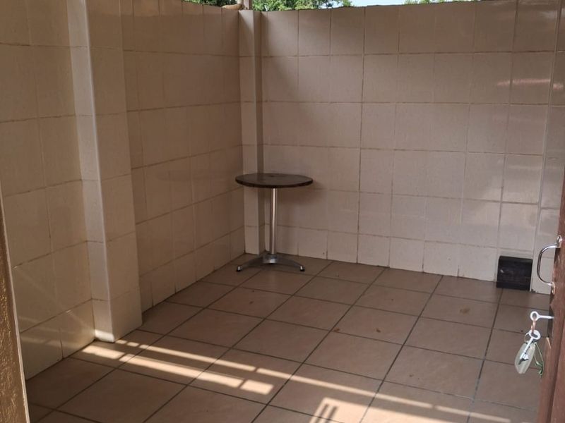 A covered outdoor patio area featuring tiled flooring and walls, providing a functional space for outdoor relaxation.