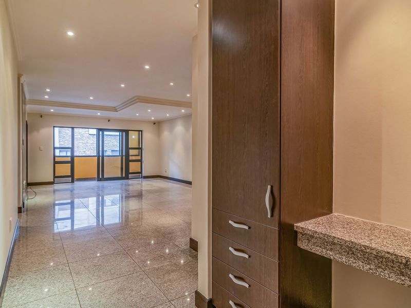 Spacious open-plan living area featuring polished granite flooring, recessed lighting, and built-in cabinetry with a granite countertop, leading to a balcony.