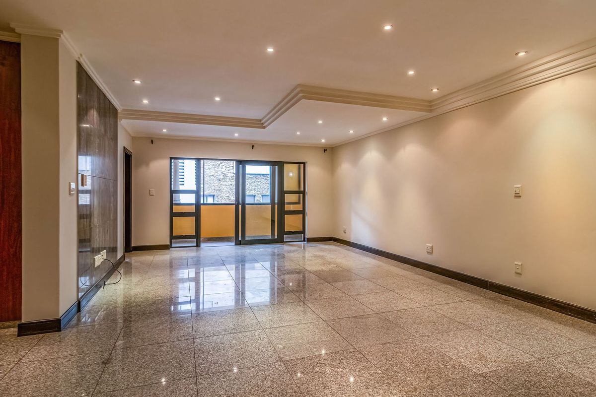 Spacious, empty living area featuring polished granite flooring, a coffered ceiling with recessed lighting, and a stone feature wall leading to a balcony.