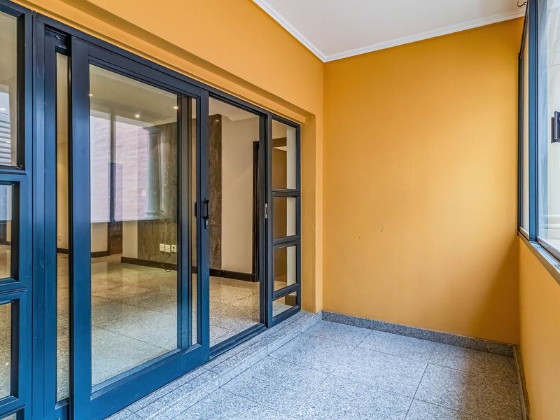 A clean, empty balcony featuring tiled flooring and large sliding glass doors providing access to the interior living space.