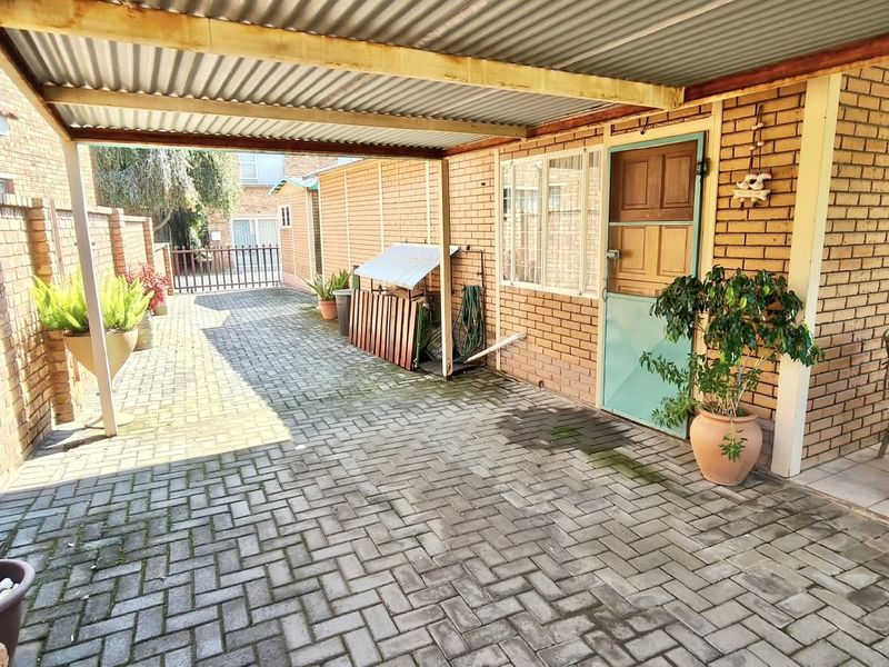 A covered outdoor patio area featuring face brick walls, corrugated metal roofing, and paved flooring, providing a functional space for outdoor living.