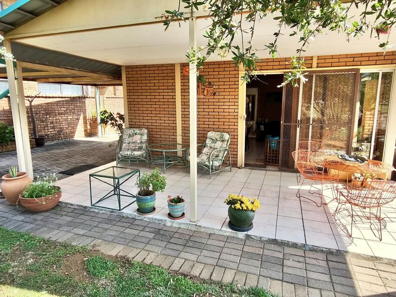 A covered outdoor patio area featuring tiled flooring, brick walls, and direct access to the interior through a sliding glass door.