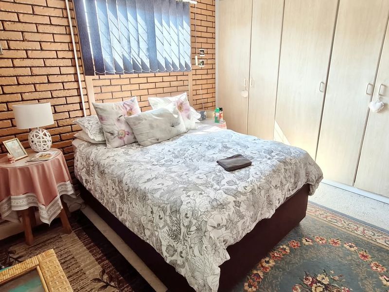 A bedroom featuring an exposed brick feature wall and ample built-in cupboard storage space.
