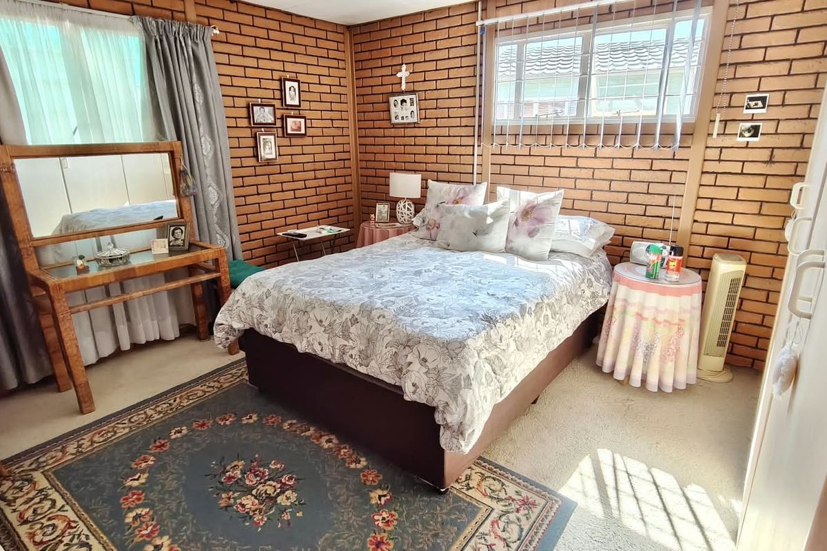 A bedroom featuring exposed brick walls and a large window, providing a rustic aesthetic with potential for modern updates.