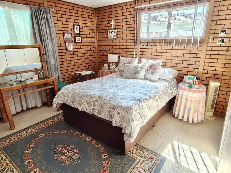 A bedroom featuring exposed brick walls and a large window, providing a rustic aesthetic with potential for modern updates.