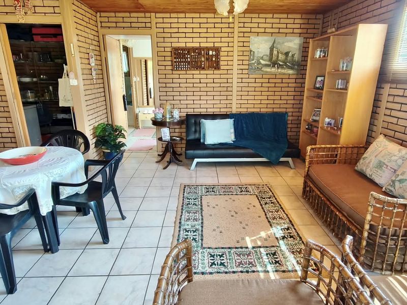 Open-plan living and dining area featuring exposed brick walls, tiled flooring, and a timber ceiling, offering a rustic and functional living space.