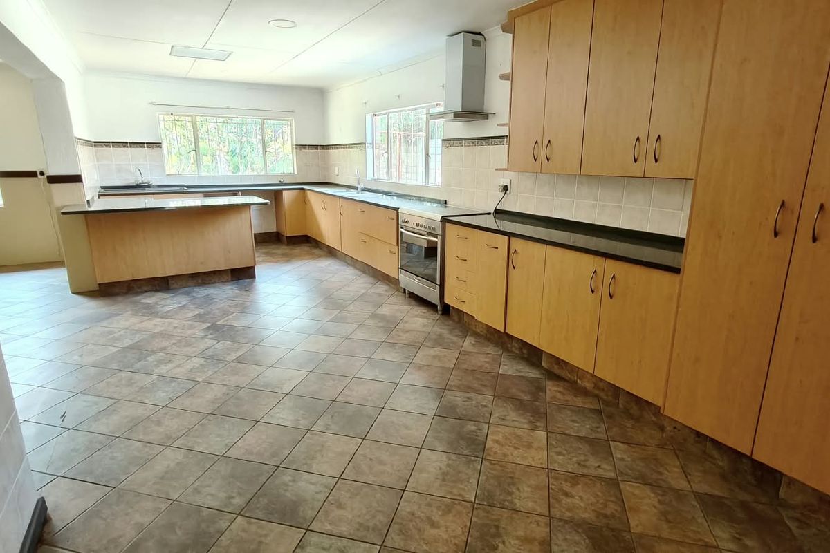 Spacious kitchen featuring extensive laminate cabinetry, granite countertops, tiled flooring, and a stainless steel extractor fan, offering a functional layout for culinary activities.