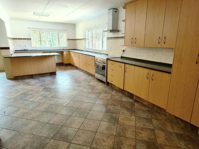 Spacious kitchen featuring extensive laminate cabinetry, granite countertops, tiled flooring, and a stainless steel extractor fan, offering a functional layout for culinary activities.