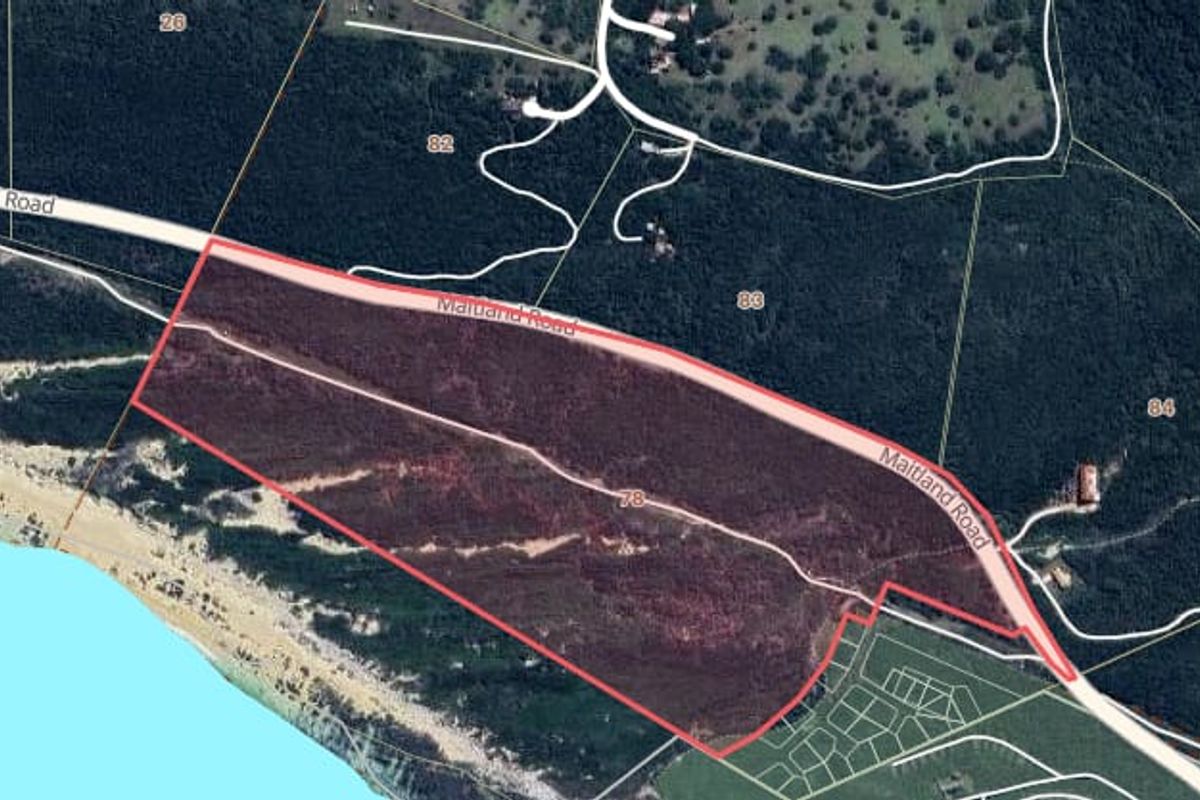 Aerial satellite view showing the property boundary lines and surrounding landscape, including proximity to the coastline and local road access.
