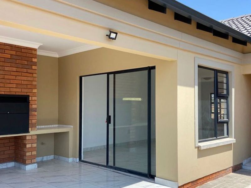 A covered patio area featuring a built-in brick braai, tiled flooring, and direct access to the interior through sliding glass doors.