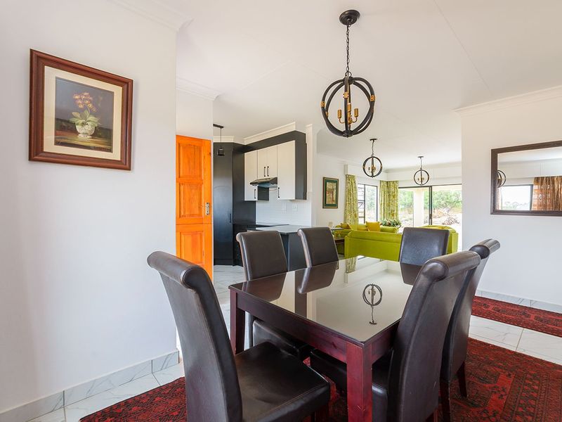 Open-plan living and dining area featuring tiled floors, modern pendant lighting, and a functional kitchen with contemporary cabinetry and an extractor fan.
