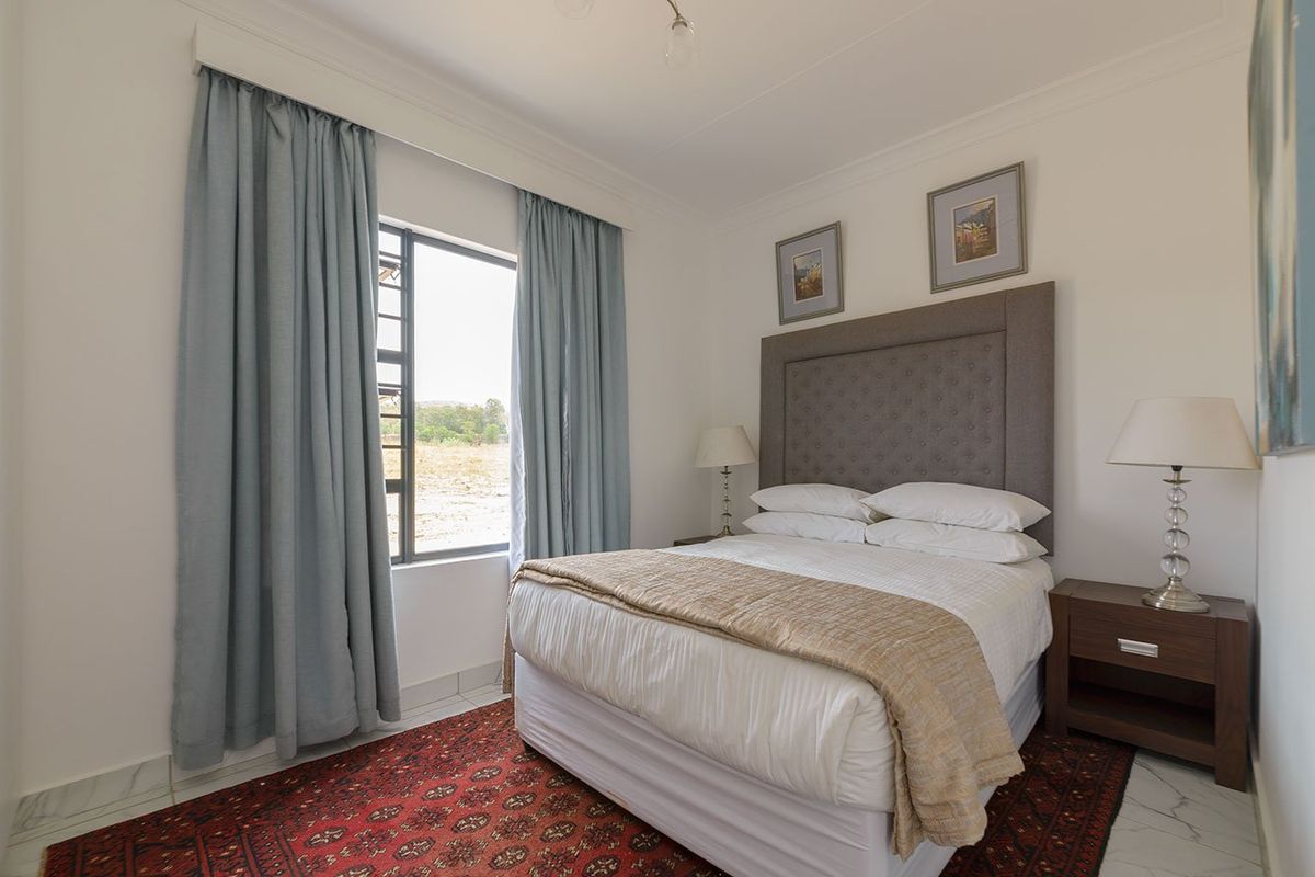 A well-maintained bedroom featuring tiled flooring, neutral walls, and a window with curtains, providing a comfortable and bright living space.