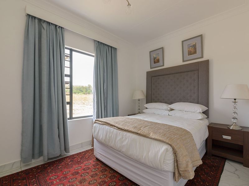 A well-maintained bedroom featuring tiled flooring, neutral walls, and a window with curtains, providing a comfortable and bright living space.