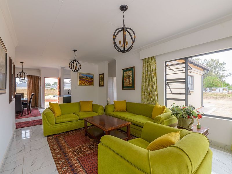 Spacious open-plan living area featuring marble-look tiled flooring, large windows providing natural light, and direct access to the outdoor space.