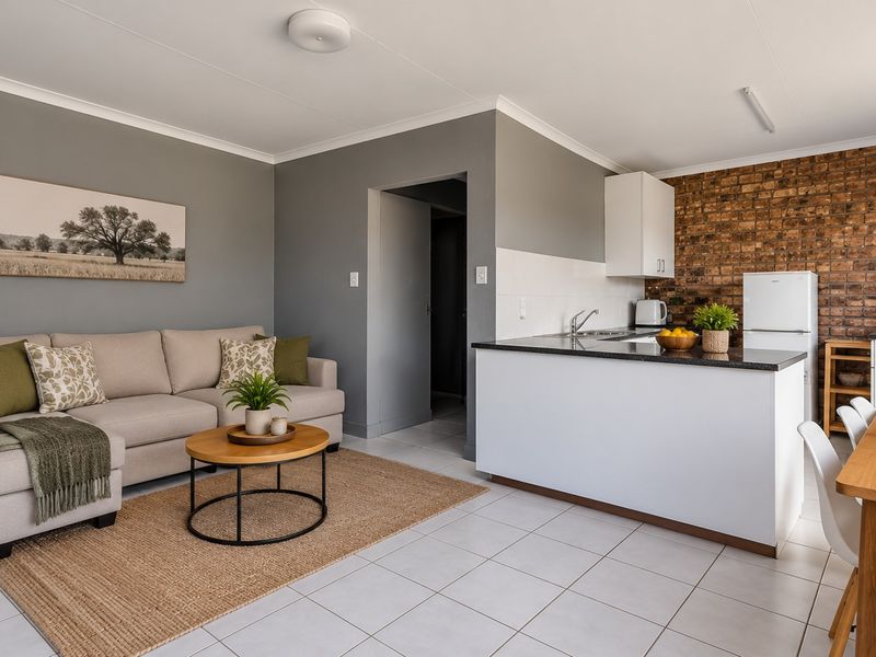 An open-plan living and kitchen area featuring tiled floors, a kitchen island, and a distinctive exposed brick feature wall.