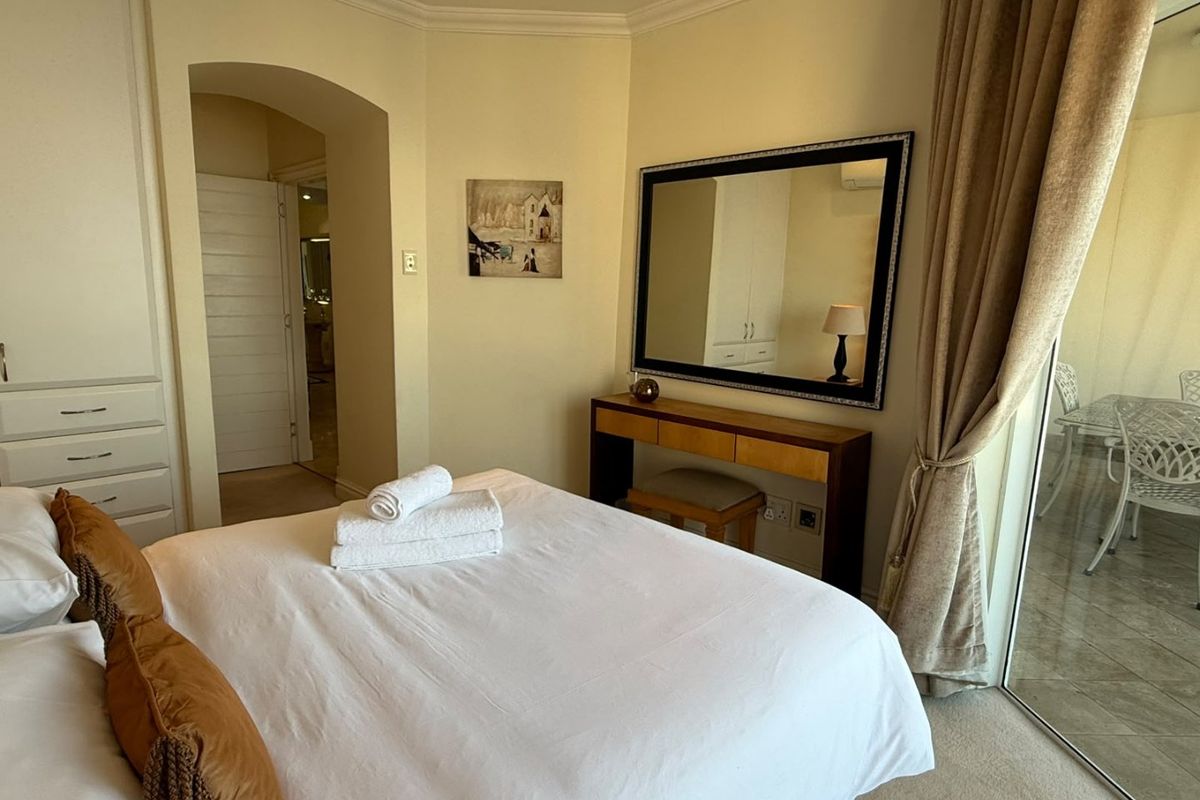 A well-maintained bedroom featuring built-in cupboards, coving, and a sliding glass door providing access to an outdoor patio area.