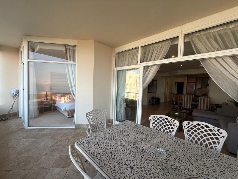 A covered balcony featuring tiled flooring and large sliding glass doors that provide seamless access to the interior living and bedroom areas.