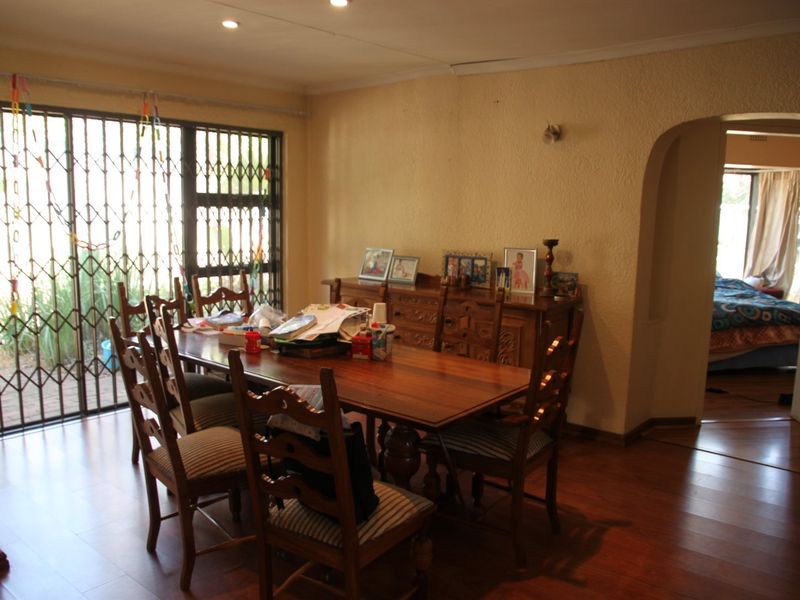 Dining room featuring laminate flooring, recessed lighting, and a security gate leading to the exterior, with an arched doorway connecting to adjacent living spaces.