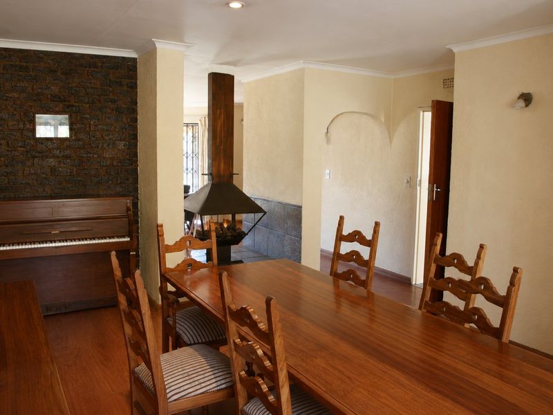 Dining area featuring an exposed brick wall, a central freestanding fireplace, and laminate flooring, leading into an adjacent living space through an archway.