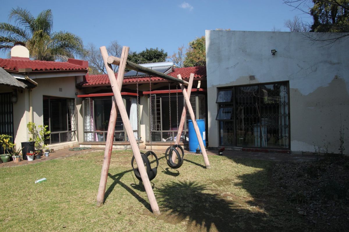 Rear view of the property featuring a garden area, solar water heating system, and security gates on the glass sliding doors.