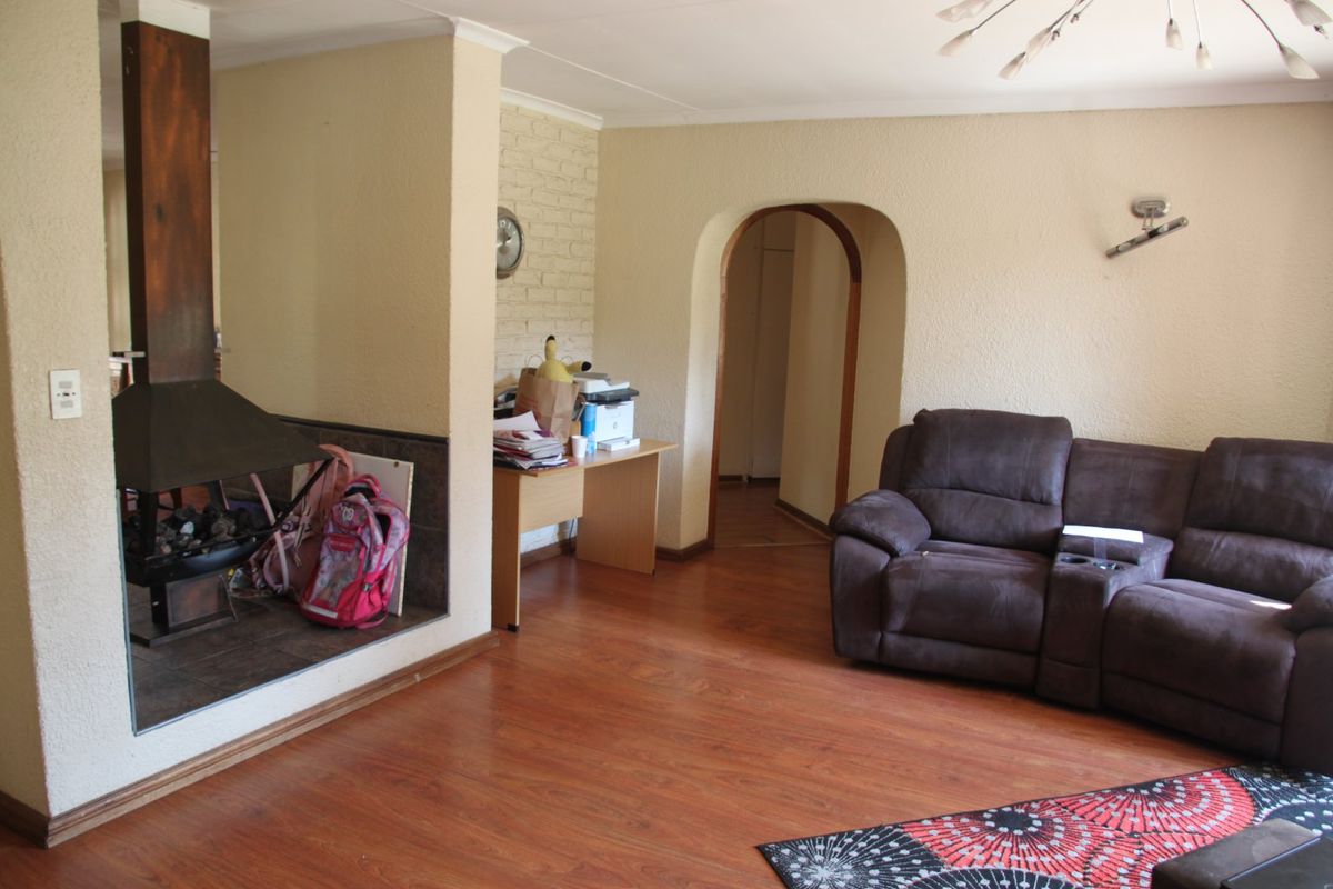 A living room featuring laminate flooring, an arched doorway, and a freestanding fireplace set against an exposed brick feature wall.